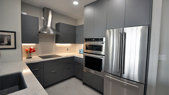 U-shaped kitchen in matte grey handleless cabinets with a stainless hood, double wall oven and French-door fridge