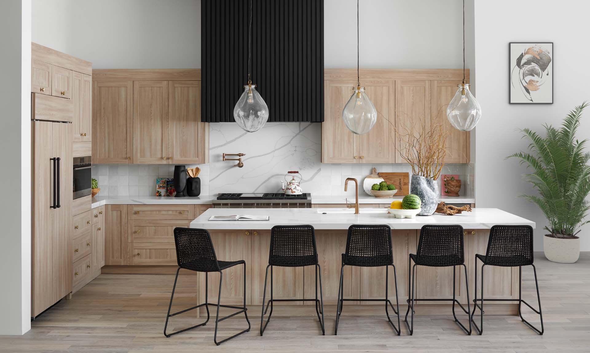 Natural oak shaker cabinets with a black fluted range hood, glass pendants and a long island
